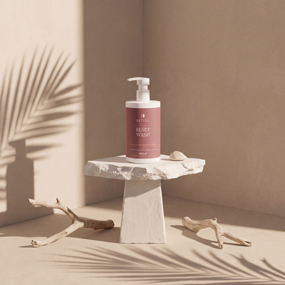 RESET WASH de Nitiel sobre un pedestal de piedra, con sombras de palmera