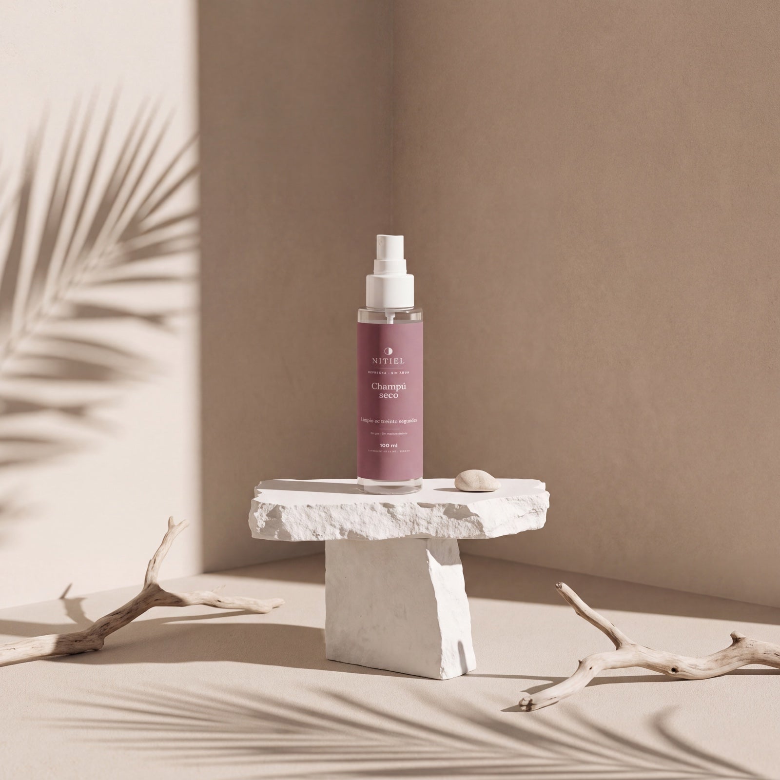 Champú seco de Nitiel sobre un pedestal de piedra, con sombras de palmera