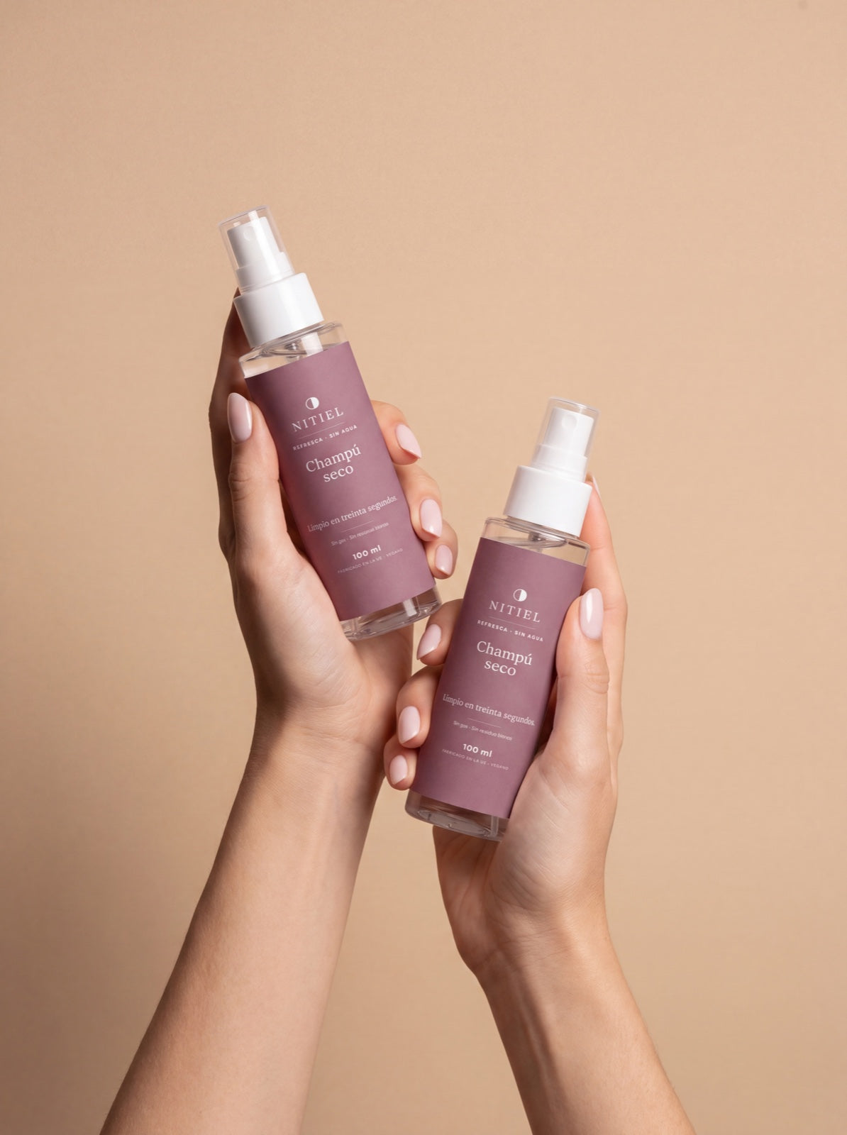 Dos sprays del champú seco de Nitiel sostenidos en las manos